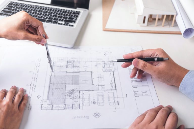 Engineering or Creative architect in construction project, Engineers hands working with compasses on construction blueprint building at a workplace in office, Building and architecture concept